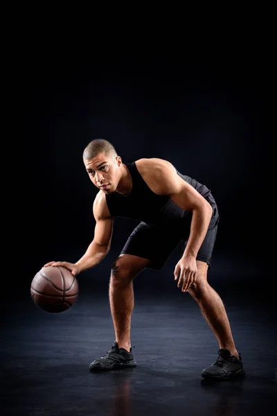 Afrikanischer amerikanischer Basketballspieler lässt Ball auf Schwarz hüpfen — Stockfoto