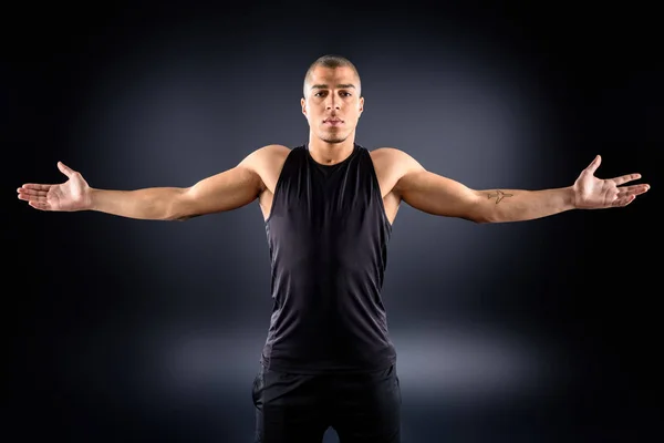 Sportivo afroamericano con le braccia tese sul nero — Foto stock