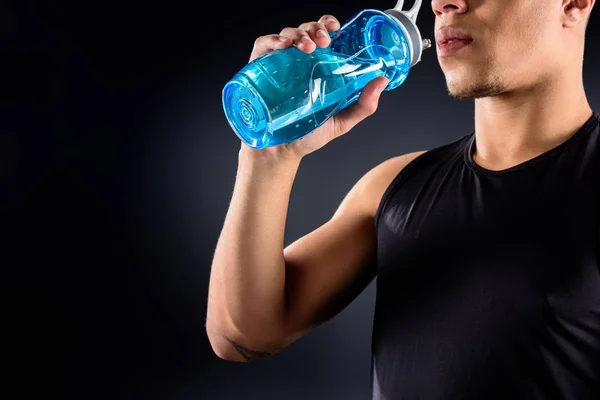 Cropped shot of african american sportsman drinking water on black — Stock Photo