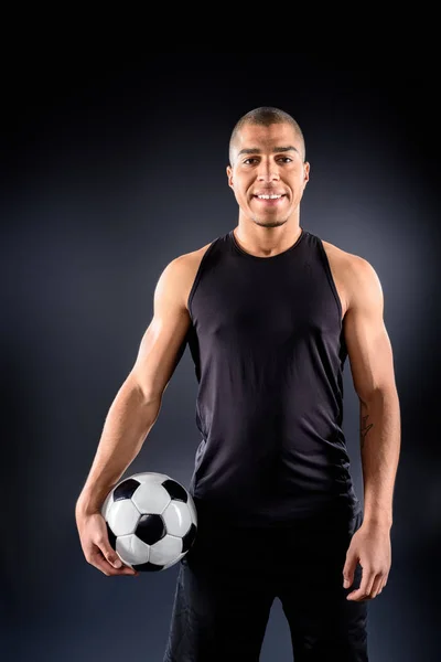 Handsome african american soccer player with ball on black — Stock Photo