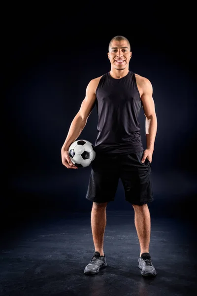 Happy african american soccer player with ball on black — Stock Photo