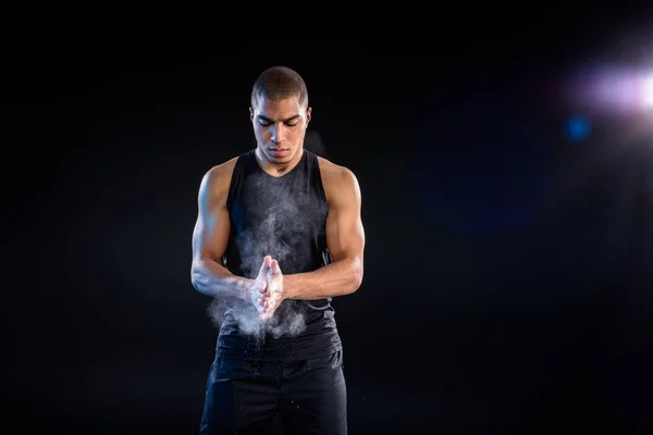 Handsome african american sportsman clapping hands with talc on black — Stock Photo