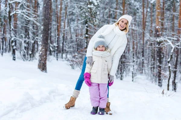 Mãe sorridente abraçando filha enquanto estava em pé no parque de inverno — Fotografia de Stock