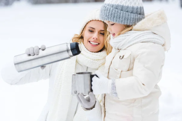 Family drinking hot tea while walking in winter forest — Stock Photo