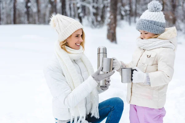 Familia bebiendo té caliente mientras camina en el bosque de invierno - foto de stock