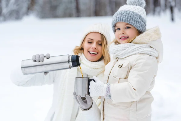 Family drinking hot tea while walking in winter forest — Stock Photo