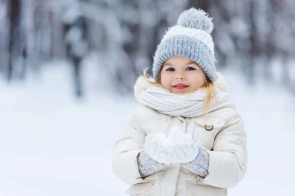 Ritratto di adorabile bambino che tiene la palla di neve in mano nel parco invernale — Foto stock