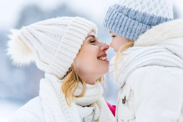 Side view of beautiful happy mother and daughter smiling each other in winter park — Stock Photo
