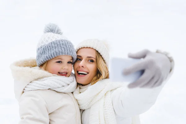 Hermosa feliz madre e hija tomando selfie en invierno parque - foto de stock