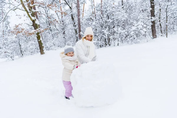 Belle mère heureuse et fille faisant bonhomme de neige dans le parc d'hiver — Photo de stock