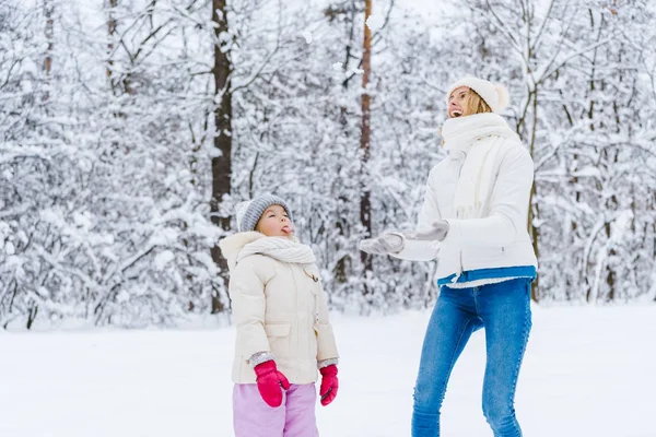 Bella madre e figlia felice guardando in alto mentre giocano insieme nel parco invernale — Foto stock