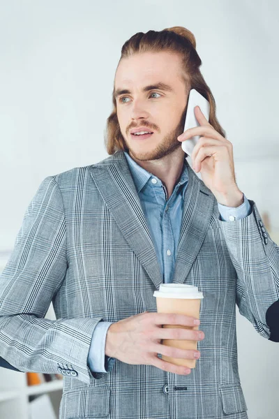 Gutaussehender Geschäftsmann, der im Büro per Smartphone spricht — Stockfoto