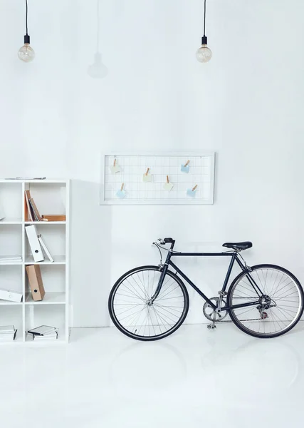 Fahrrad neben Holzregalen in leerem Büro — Stockfoto