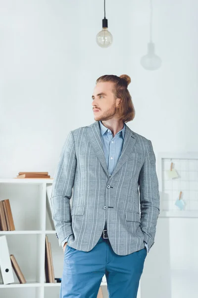 Handsome businessman standing in office and looking away — Stock Photo