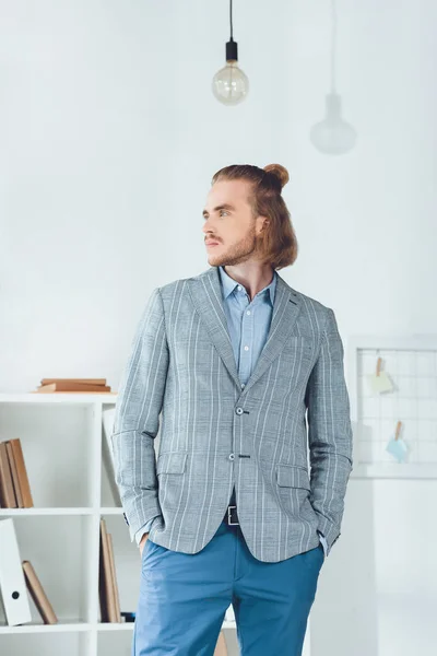 Hombre de negocios guapo de pie en la oficina y mirando hacia otro lado - foto de stock