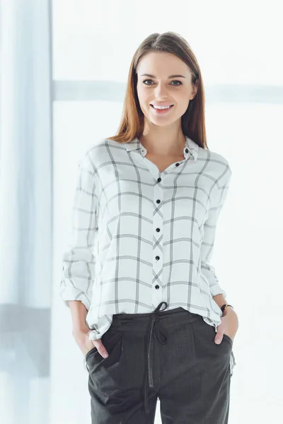 Sonriente mujer de negocios de pie y mirando a la cámara - foto de stock