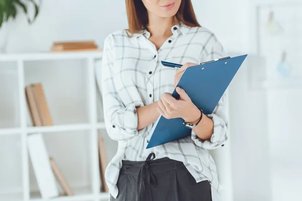 Abgeschnittenes Bild einer Geschäftsfrau, die in Klemmbrett schreibt — Stockfoto