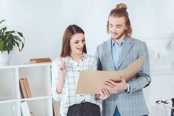 Businesswoman showing idea gesture when looking at documents in folder — Stock Photo