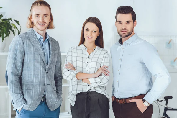 Smiling caucasian businesspeople standing in office and looking at camera — Stock Photo