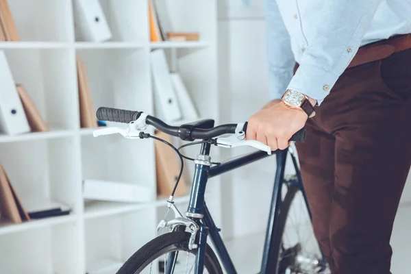 Immagine ritagliata di uomo d'affari che tiene la bici in ufficio — Foto stock