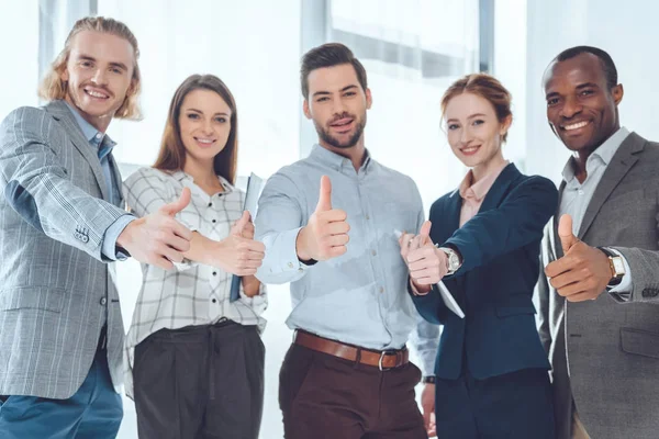 Empresários multiculturais sorridentes mostrando polegares para cima — Fotografia de Stock