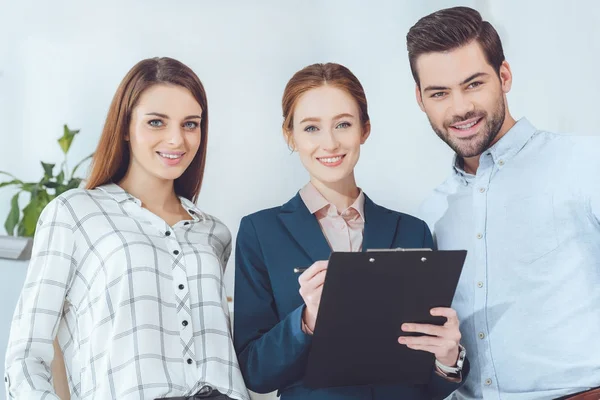 Lächelnde Geschäftsleute, die stehen und in die Kamera schauen — Stockfoto