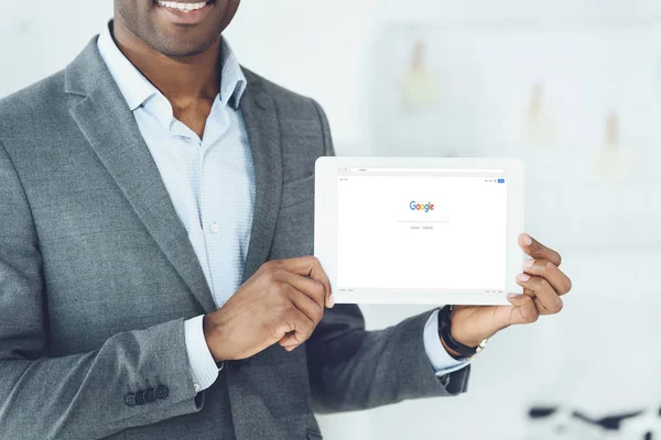 Image recadrée de souriant homme afro-américain montrant tablette avec page google chargé — Photo de stock