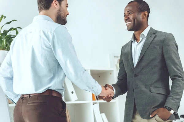 Sorridentes empresários afro-americanos e caucasianos apertando as mãos — Fotografia de Stock