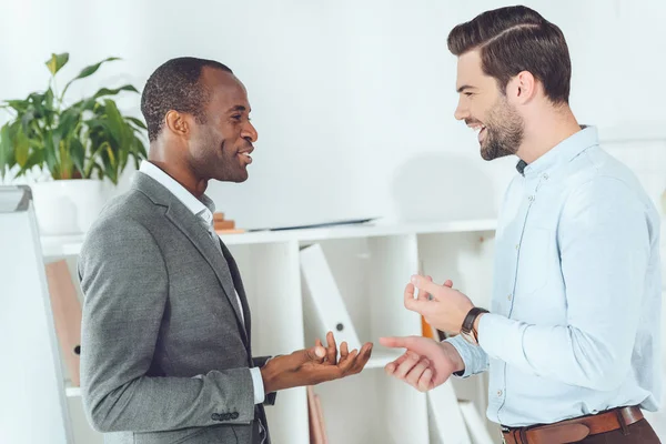 Sorridentes empresários afro-americanos e caucasianos conversando no escritório — Fotografia de Stock
