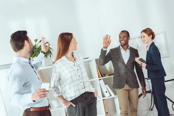 Souriant multiculturel hommes d'affaires agitant les mains dans le bureau — Photo de stock