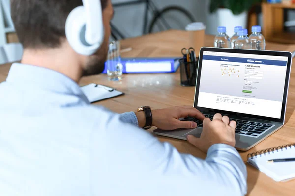 Businessman using laptop with loaded facebook page — Stock Photo