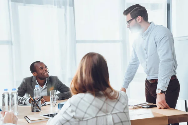 Sonrientes empresarios multiétnicos en la reunión en el cargo - foto de stock