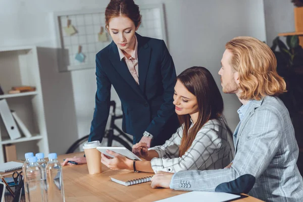 Empresarios atractivos mirando tableta en la oficina - foto de stock