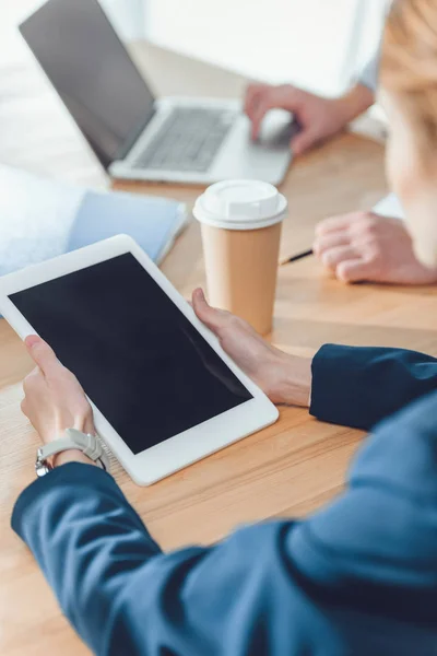 Imagem recortada de mulher segurando tablet digital enquanto sentado à mesa — Fotografia de Stock