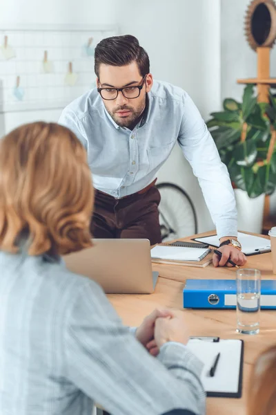 Standing man against laptop on table  at office space — Stock Photo