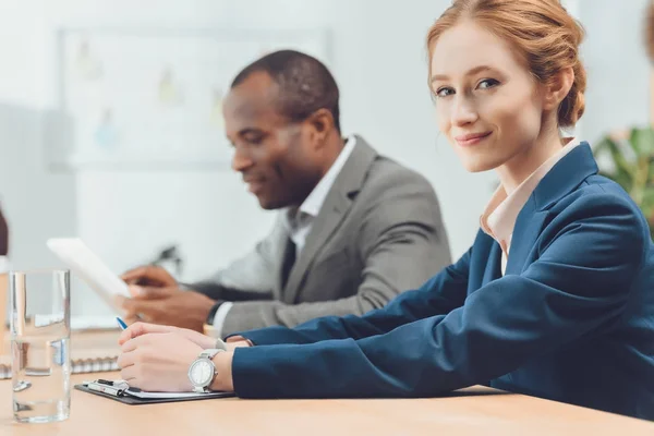 Woman in formal suit looking at camera at office space — Stock Photo