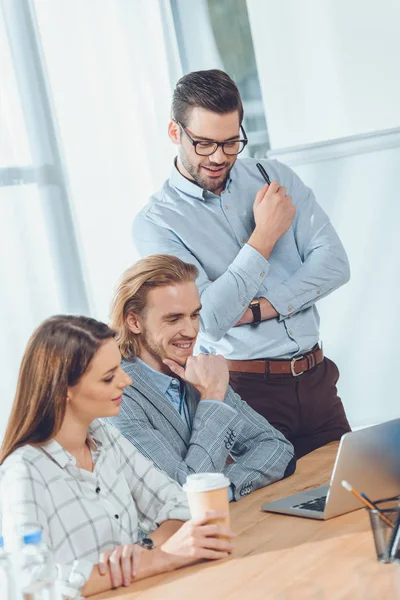 Équipe d'affaires regardant sur ordinateur portable sur la table à l'espace de bureau — Photo de stock