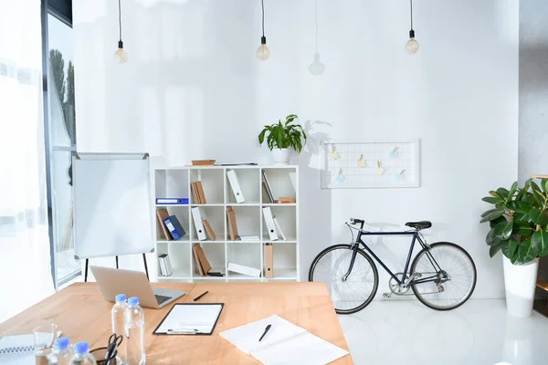 Вид на порожній офісний інтер'єр зі столом і велосипедом на стіну — стокове фото