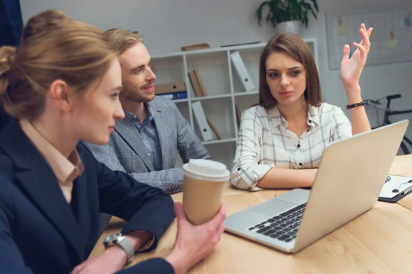 Equipo de negocios tienen discusión mientras está sentado en la mesa con el ordenador portátil - foto de stock