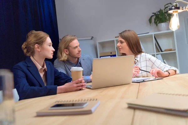 Team di lavoro hanno discussione mentre seduto a tavola con il computer portatile — Foto stock