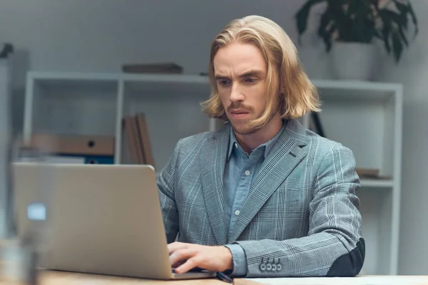 Uomo caucasico che utilizza il computer portatile sul tavolo in ufficio — Foto stock
