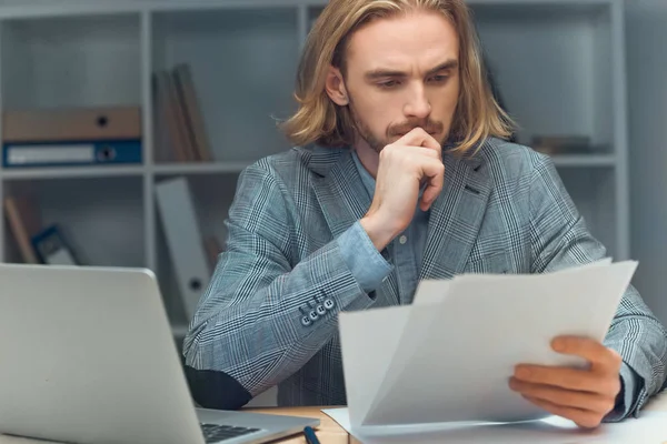 Pensive caucasian man holding paper while sitting at table — Stock Photo