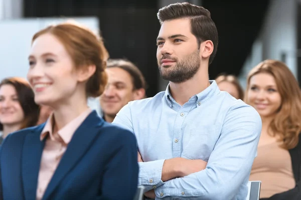 Caucásico hombre de camisa azul mirando hacia otro lado mientras está sentado en la reunión - foto de stock