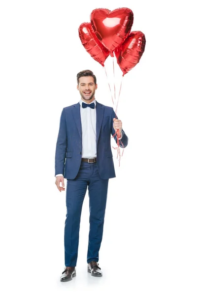Щасливий молодий чоловік з повітряними кулями у формі серця ізольований на білому — стокове фото