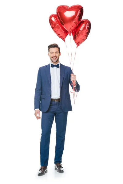 Joven feliz con globos en forma de corazón aislados en blanco - foto de stock