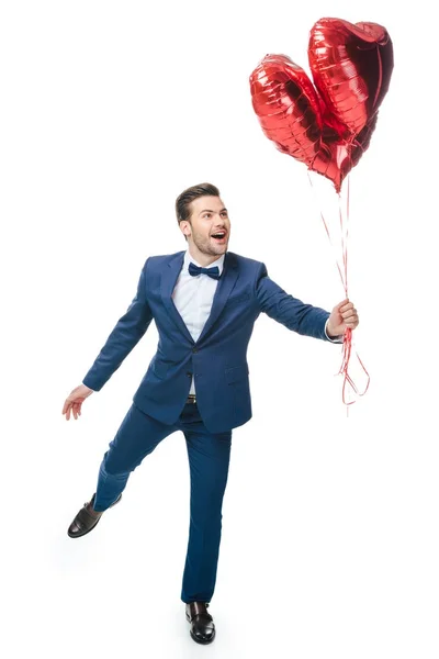 Щасливий молодий чоловік з повітряними кулями у формі серця ізольований на білому — стокове фото