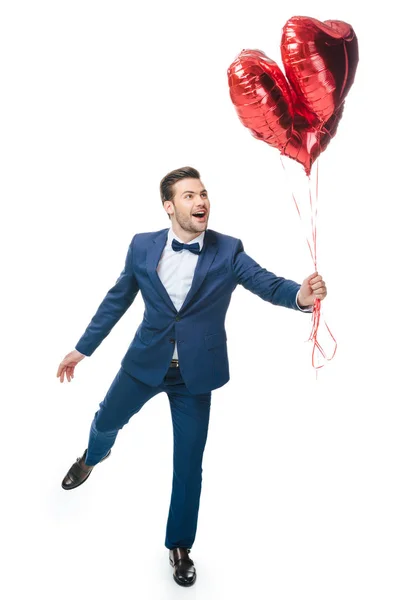 Joven feliz con globos en forma de corazón aislados en blanco - foto de stock