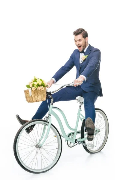 Счастливый жених в костюме верхом на ретро велосипеде со свадебным букетом в корзине изолированы на белом — стоковое фото
