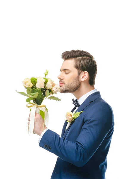 Vista lateral del novio con ramo de bodas en mano aislado en blanco - foto de stock