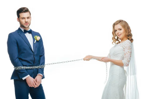 Young bride holding groom on chain isolated on white — Stock Photo